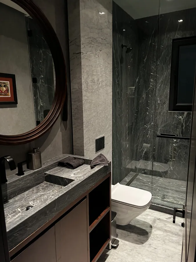 Baño de mármol con regadera y espejo circular — casa residencial construida por Prisma Habita en Puebla