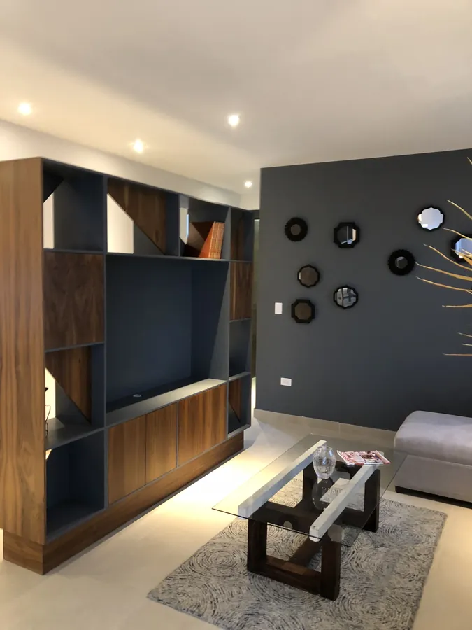 Sala con muro de TV oscuro y mueble de madera — casa residencial construida por Prisma Habita en Puebla