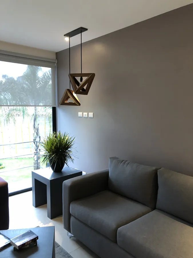 Sala con sofá gris y ventanal al jardín — casa residencial construida por Prisma Habita en Puebla