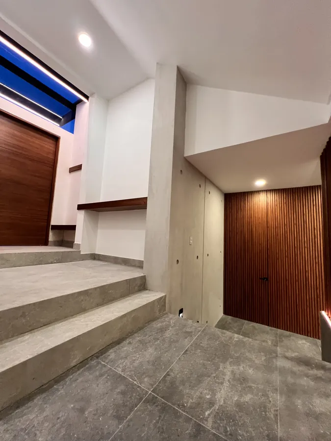 Acceso interior con escalones y muro de madera — residencia contemporánea de doble altura en Puebla