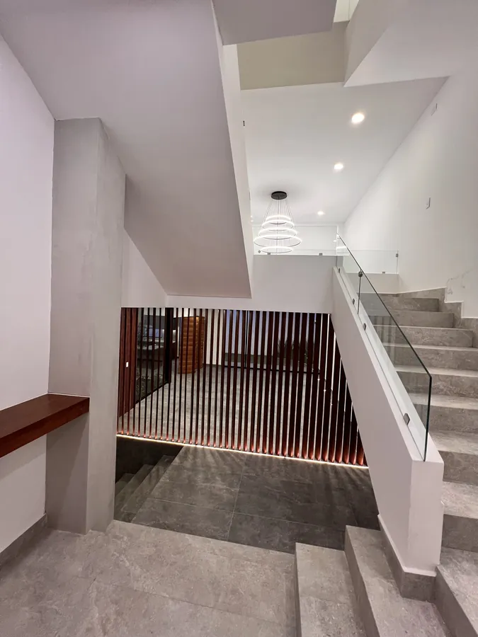 Escalera con muro de madera y barandal de cristal — residencia contemporánea de doble altura en Puebla