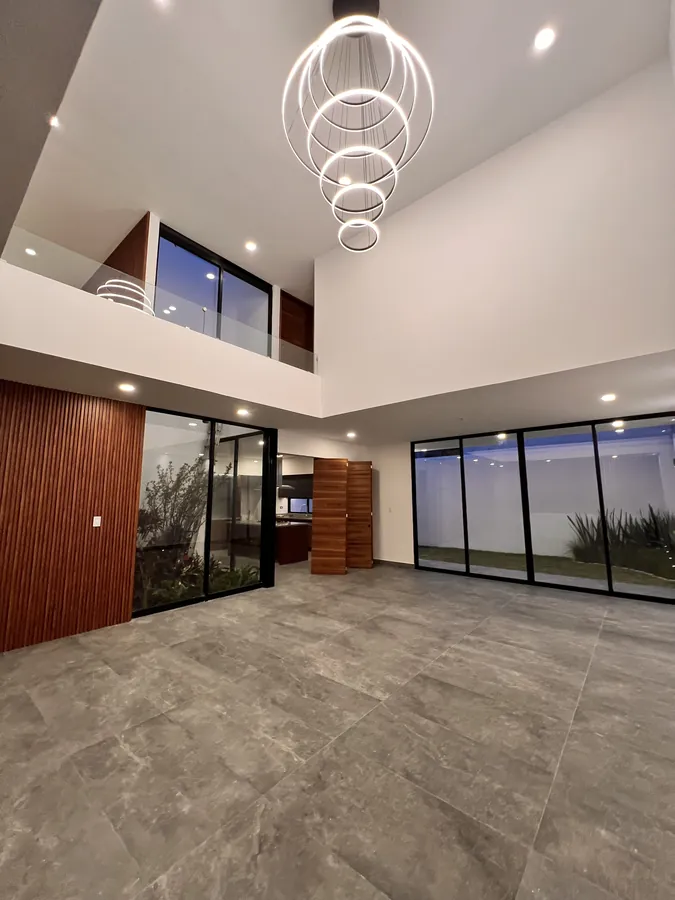 Estancia de doble altura con candil de esferas abierta al jardín — residencia contemporánea de doble altura en Puebla
