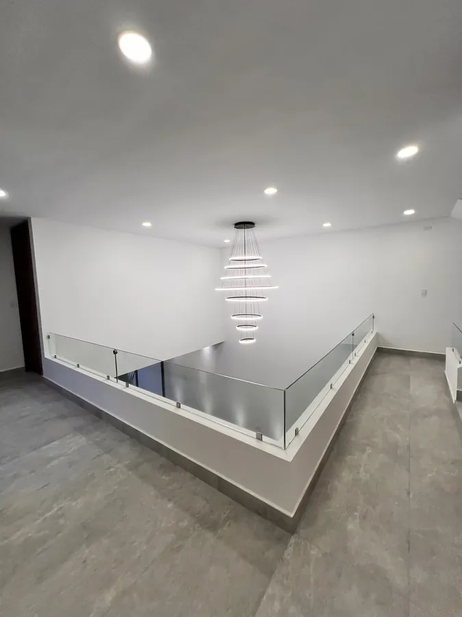 Vestíbulo a doble altura con barandal de cristal — residencia contemporánea de doble altura en Puebla