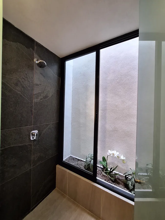 Baño con muros de piedra y ventana con vegetación — casa Missouri 99 en el corredor Angelópolis, Puebla
