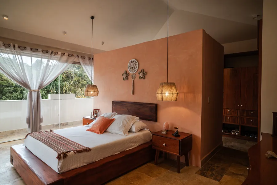 Recámara principal con muro terracota y lámparas de fibra — casa residencial de autor en Atlixco, Puebla