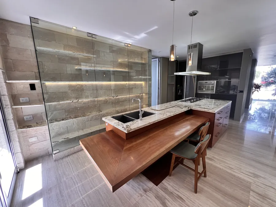 Cocina con muro de ónix retroiluminado e isla de cascada — penthouse en Lomas de Angelópolis, Puebla