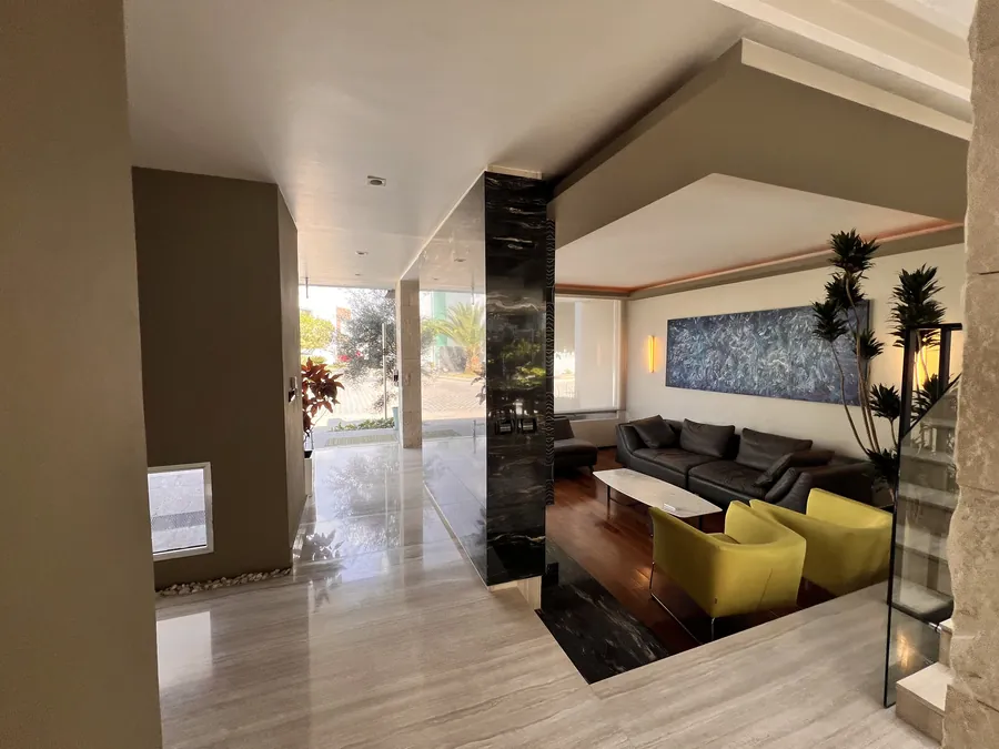Sala cálida con sofá en tono olivo y arte — penthouse en Lomas de Angelópolis, Puebla